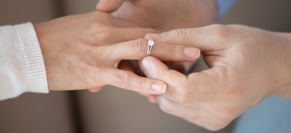 a man putting a wedding ring on a womans finger