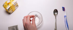 a woman placing an engagement ring in cleaning solution