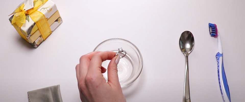 a woman placing an engagement ring in cleaning solution