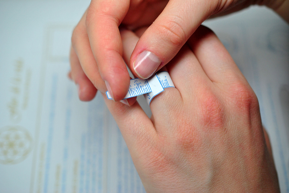 a person measuring their ring size with a fabric measuring tape