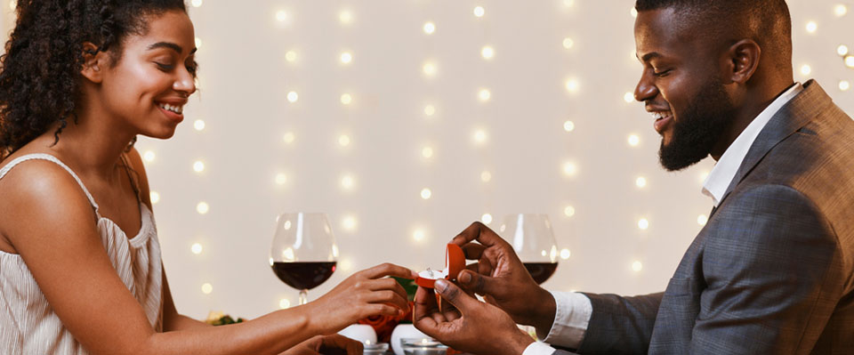 man placing engagement ring on fiancees finger